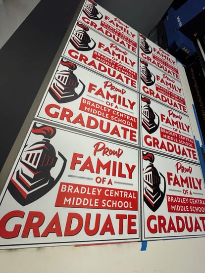 An image of several red and white middle school graduate signs.